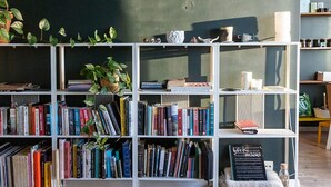 Uma estante cheia de livros e uma pequena lousa com a inscrição 'Sick Archives'.