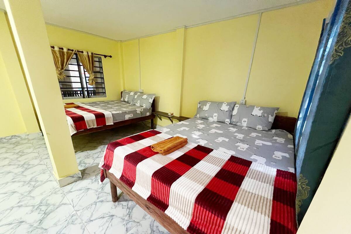 A hotel room with two beds, a marble floor, and a window with curtains.