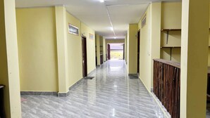 A long, narrow hallway with marble flooring and yellow walls. - Para Hostel Koh Rong (Koh Rong)