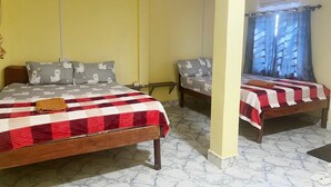 A room with two beds, each with a red and white checkered bedspread and pillows with a white animal print. The walls are yellow, and there is a window with blue curtains. - Para Hostel Koh Rong (Koh Rong)