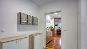 Un pasillo con casilleros, un armario de madera y una puerta que da a una habitación con una planta y un cuadro.
