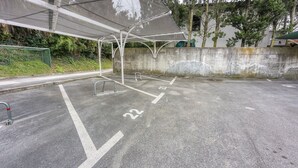 Un área de estacionamiento con espacios delimitados, una barrera metálica y un muro de concreto.