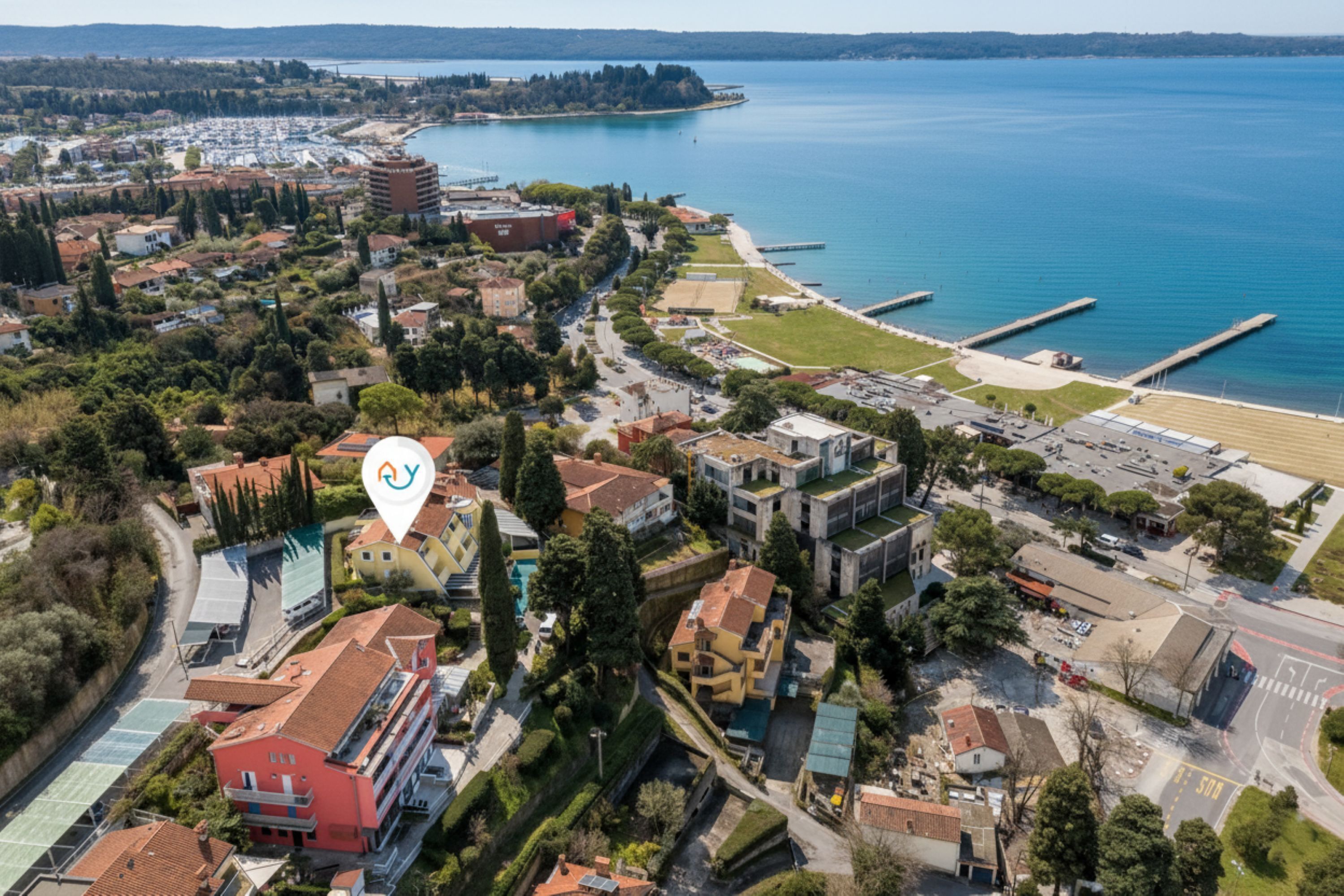 Vue aérienne d’une ville côtière avec un port de plaisance, des bâtiments et une plage.