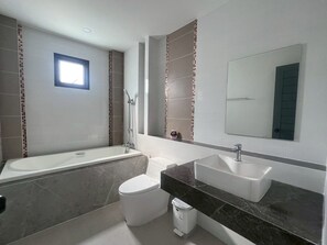 Une salle de bain moderne équipée d’une baignoire, de toilettes et d’un lavabo.