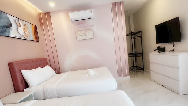 A hotel room with two beds, a white dresser, a TV, and an air conditioning unit.