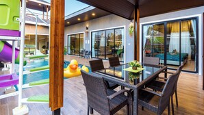 A modern outdoor patio with a pool, wicker furniture, and a slide. - OC Breeze Casa Private Pool Villa With 3 Bedrooms, Near Cha-am Beach (Cha-am)