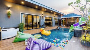 An outdoor swimming pool area with a slide, inflatable duck, and colorful balls. - OC Breeze Casa Private Pool Villa With 3 Bedrooms, Near Cha-am Beach (Cha-am)