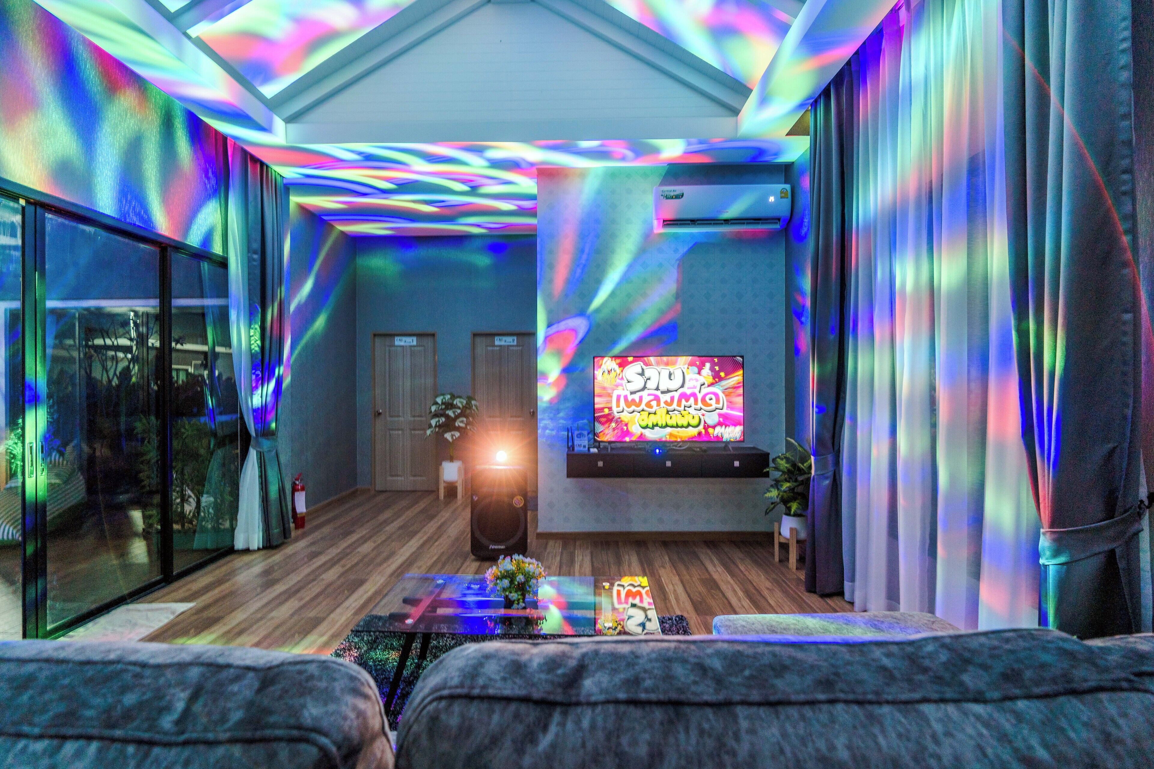 Una sala de estar moderna con un televisor de pantalla plana grande, una mesa de centro de madera con objetos decorativos y un separador de vidrio.