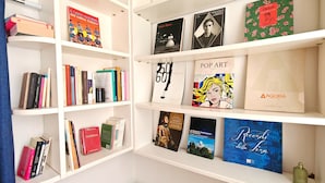 Una libreria con diversi libri e opere d'arte, tra cui un libro e una rivista di pop art anni '60.