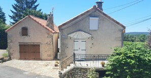 A two-story building with a stone facade, a wooden door, and a small balcony with a metal railing. - 3-Star Vacation Rentals in La Couvertoirade: "LE VIADUC" (La Couvertoirade)