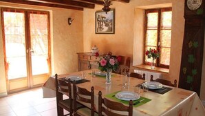 Una sala menjador amb una taula preparada per a quatre, cadires de fusta, un vas amb flors i un quadre a la paret.