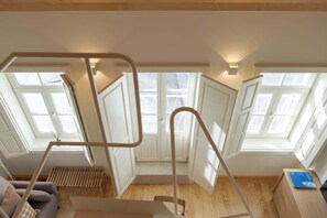 A high-ceilinged room with skylights, a wooden floor, and a staircase with metal railings. - Republica 139 Apartamentos by DA'Home #3E (Porto)
