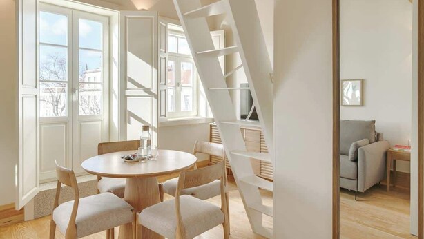 Un intérieur moderne avec une table de salle à manger ronde, des chaises, un escalier et un canapé.