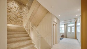 Eine Treppe mit einer Steinsäule auf einer Seite und einer weißen Wand auf der anderen, die zu einer Tür oben führt.