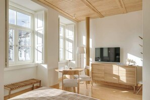 A modern bedroom with a bed, a TV, a wooden bench, a desk, and a chair. - Republica 139 Apartamentos by DA'Home #1E (Porto)
