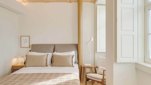 Ein Schlafzimmer mit Bett, Nachttisch, Stuhl und einem Fenster mit Blick.