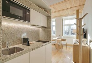 A modern kitchen with a Bosch microwave, granite countertop, and a dining area with a round table and chairs. - Republica 139 Apartamentos by DA'Home #1E (Porto)