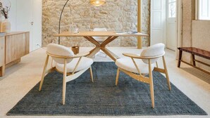 Un'area pranzo moderna con parete in pietra, soffitto in legno e un tavolo rotondo con quattro sedie.