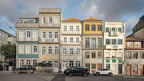 Una fila di edifici a più piani con balconi, auto parcheggiate e un cielo sereno.