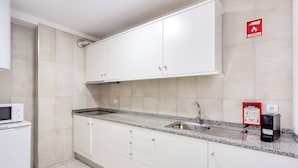 Eine moderne Küche mit weißen Schränken, einer Granit Arbeitsplatte, einer eingebauten Mikrowelle, einem Spülbecken und einem Feuerlöscher.