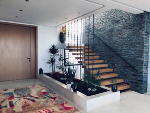 Eine moderne Treppe mit einer Steinsäule, Holzstufen und Metallgeländern.