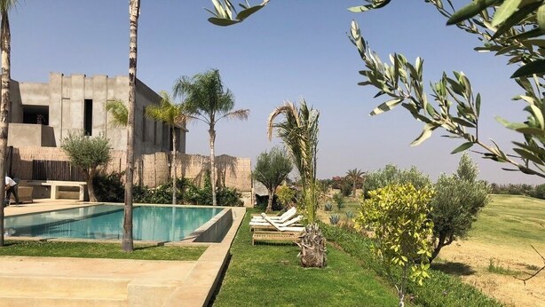 Ein modernes Haus mit Swimmingpool, einem gepflegten Rasen und verschiedenen Bäumen.