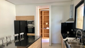 Eine moderne Küche mit schwarzen Geräten, einem Holflanschrank und einem Fliesenboden.