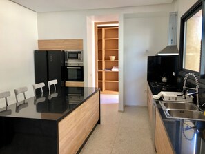 Eine moderne Küche mit schwarzen Geräten, einem Holflanschrank und einem Fliesenboden.