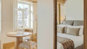 Ein Schlafzimmer mit einem Bett, einem Nachttisch, einem Sessel und einem Fenster.