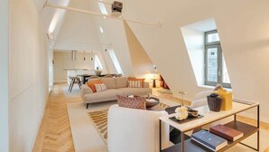 Um amplo apartamento tipo loft com pé-alto, área de refeições e um espaço de estar aconchegante com sofá e mesa de centro.
