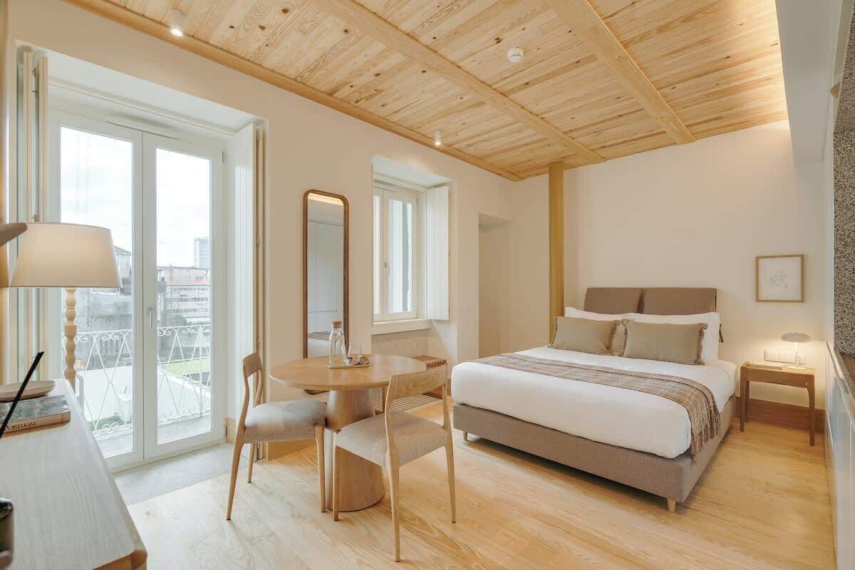 Une chambre moderne avec un grand lit, une table ronde avec des chaises, un bureau et un balcon avec vue.