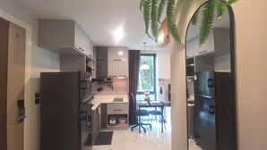 Una cocina moderna con armarios oscuros, una zona de comedor con mesa y sillas, y un ventanal que proporciona luz natural.
