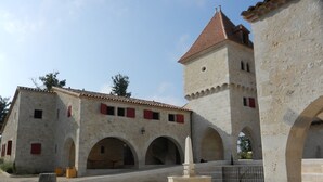 A historic building with a central courtyard, stone walls, and a tower with a red-tiled roof. - Gite du Pigeonnier and its tower with terraces and garden (Castelnau-sur-l'Auvignon)