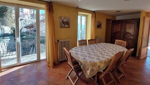 Een eetruimte met een tafel en stoelen, een radiator en uitzicht door een schuifdeur.