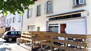Un restaurante con terraza y un coche aparcado cerca.