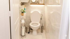 Un baño moderno con inodoro, lavamanos, espejo y repisas con artículos de aseo.