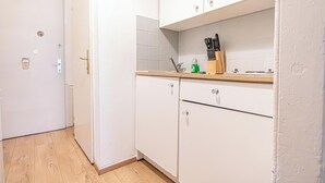 A compact kitchen with white cabinets, a wooden countertop, and a sink. - Cozy 2BR Apt With Excellent Connectivity (Vienna)