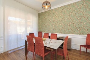A dining area with a white table, red chairs, and a floral wallpaper. - Principina (Stresa)
