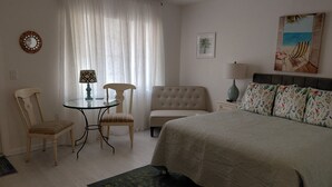 Een slaapkamer met een bed, een stoel, een klein tafeltje en een nachtkastje.