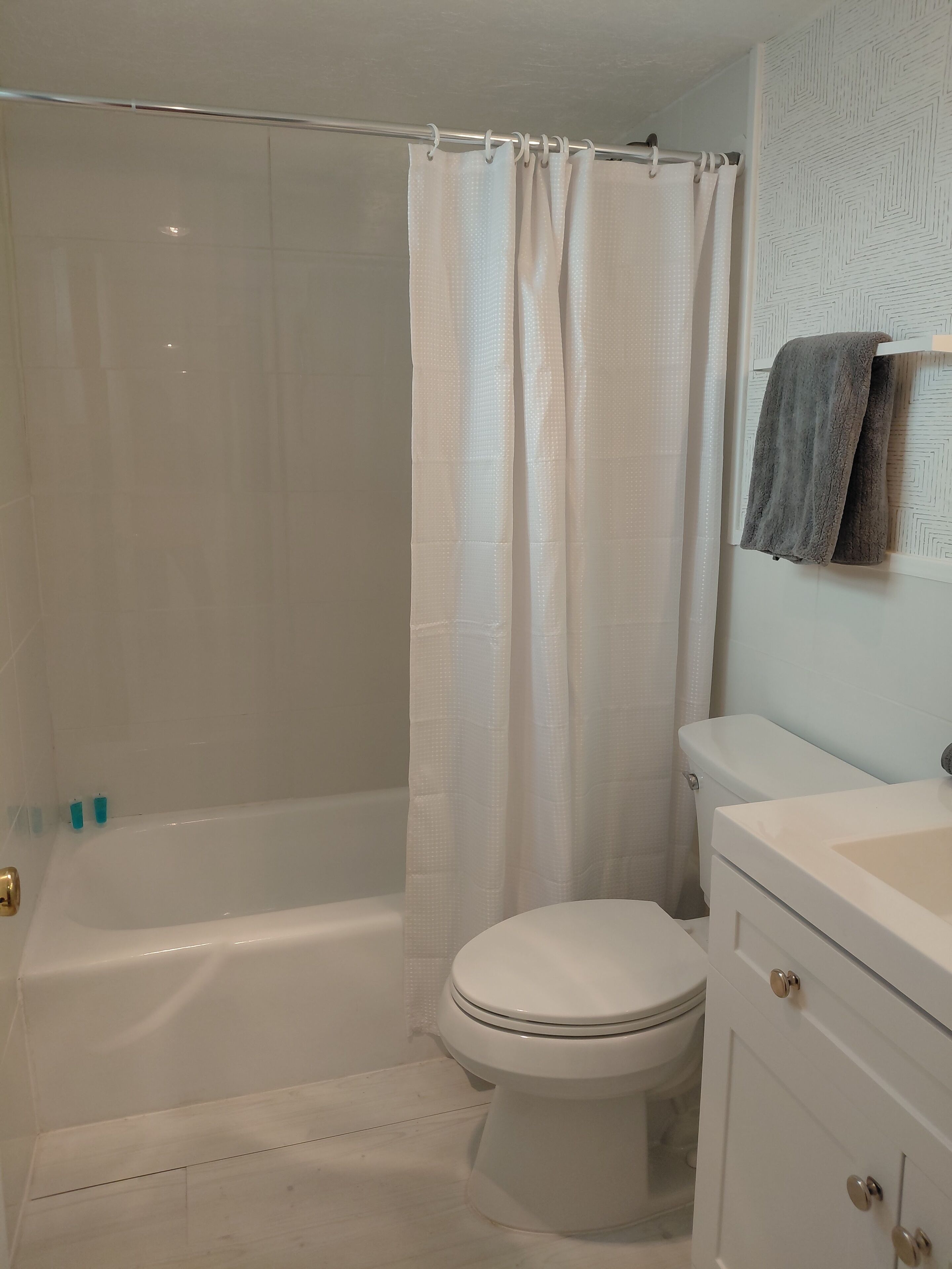 A bathroom with a bathtub, toilet, and a towel rack.