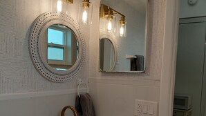 Een badkamer met een witte wastafel, twee spiegels en een handdoekhouder.