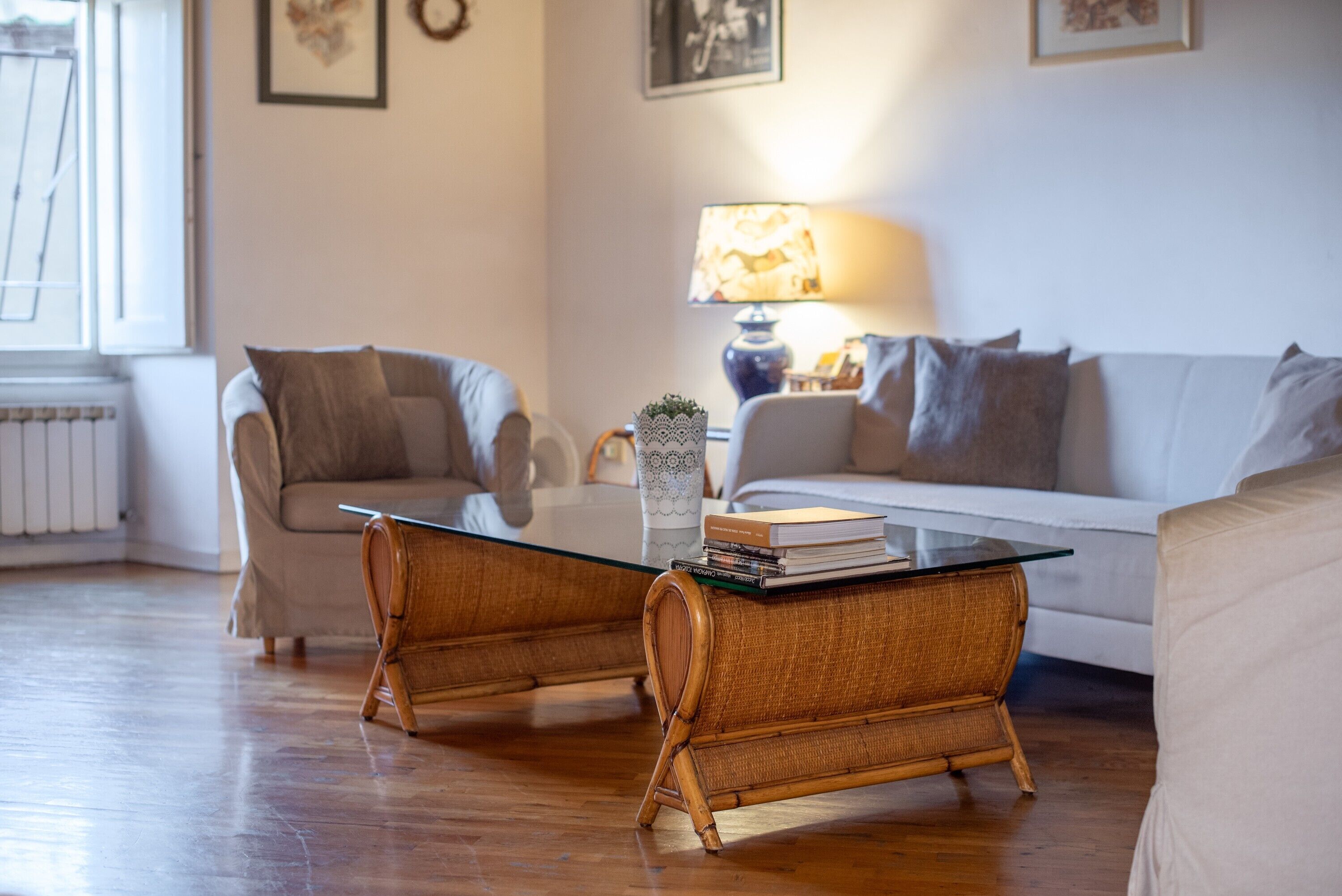 A living room with a sofa, two side tables, a lamp, and a radiator.
