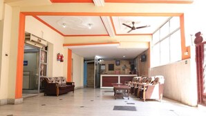 A spacious lobby with a reception desk, seating area, and a ceiling fan. - New Samrat Hotel And Restaurant (Srinagar)