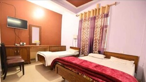 A bedroom with two beds, a TV, a mirror, and a desk. - New Samrat Hotel And Restaurant (Srinagar)