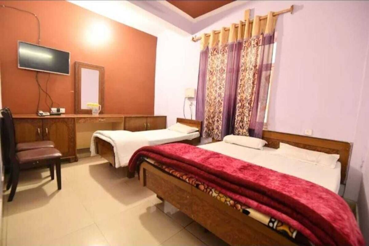 A bedroom with two beds, a TV, a mirror, and a desk.