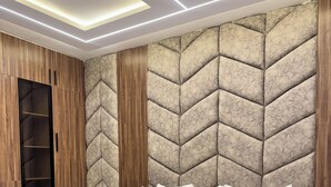 A modern bedroom with a large bed, wooden wardrobe, and a unique textured headboard. - Lumora Apartments (Abuja)