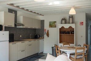 Eine kompakte Küche mit weißen Schränken, einem eingebauten Backofen und einem Essbereich mit rundem Tisch und Stühlen.