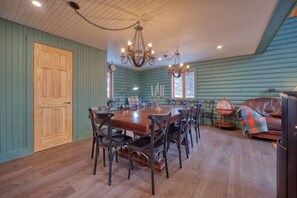 Ein Esszimmer mit Holztisch und -stühlen, einer Kronleuchter und einer Ledersitzbank.