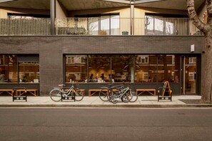 A modern building with large windows, a balcony, and bicycles parked outside. - Central 3BR Home Near Tower Bridge with Garden, Parking & Dog-Friendly (London)