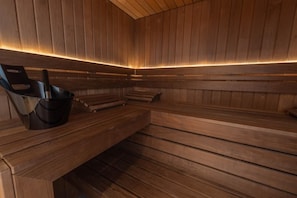 A sauna with wooden benches and a black sauna chair. - Chalet Combloux, Megève, Mont-Blanc View (Combloux)